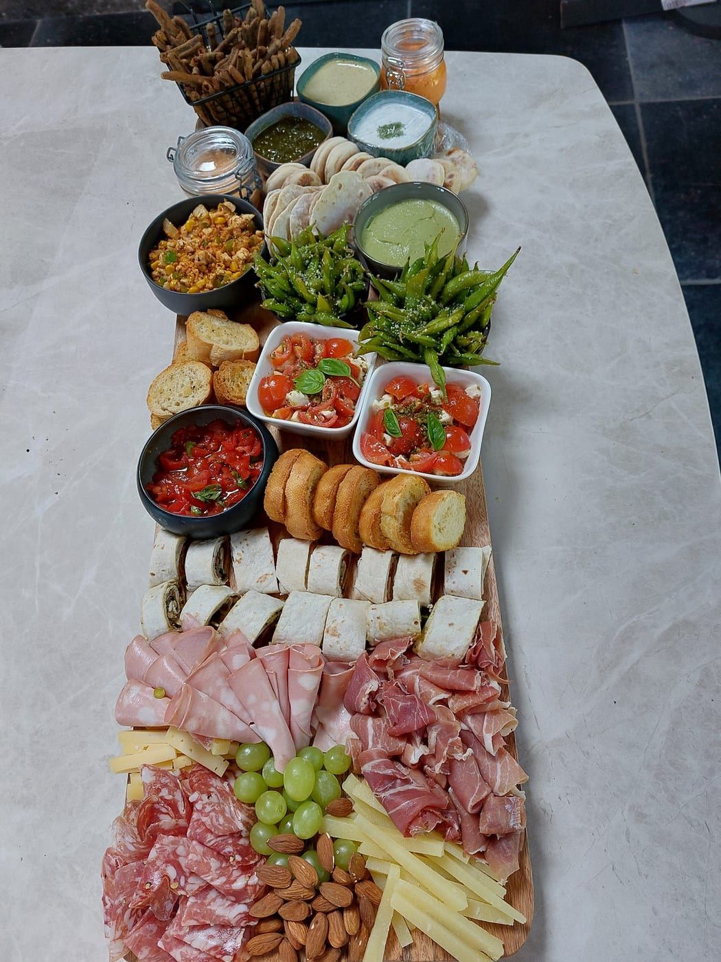 Tapasplank Colette, rijkelijk gevuld met kaas, charcuterie, dips, olijven en broodjes